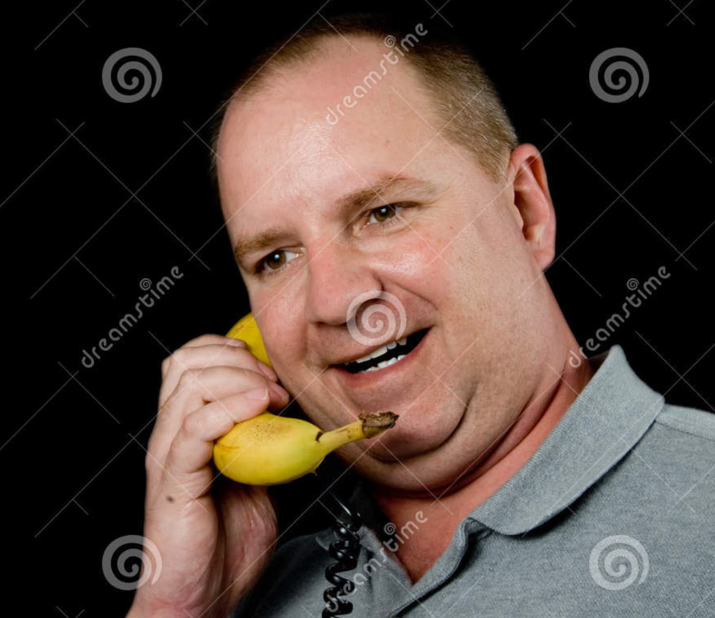 Stock image, with watermark, of a cheery man holding a banana to his ear like a telephone